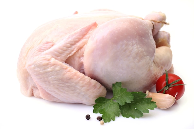 Chicken on a white surface with parsley leaves and tomato