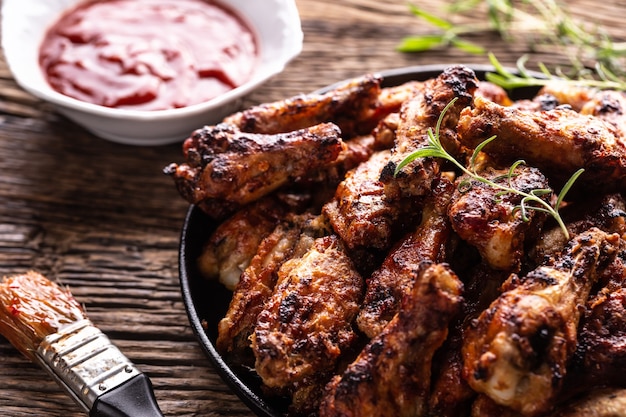 Chicken wings barbeque in een gietijzeren ovenschaal met BBQ saus en rozemarijn.