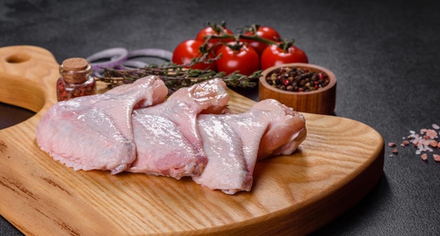 Chicken wings lie on a wooden board on a black background