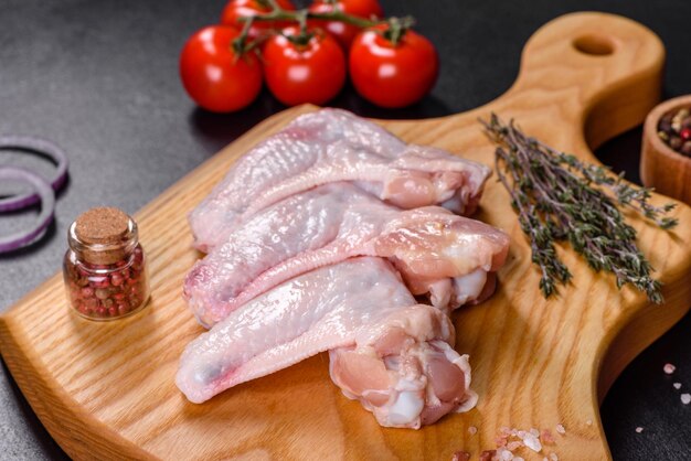 Chicken wings lie on a wooden board on a black background