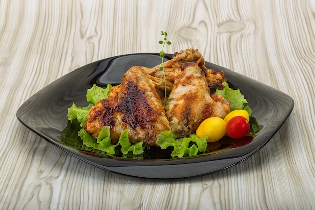 Chicken wings roasted served with salad leaves thyme and tomato