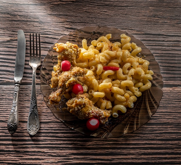 Chicken wings with pasta on a wooden table