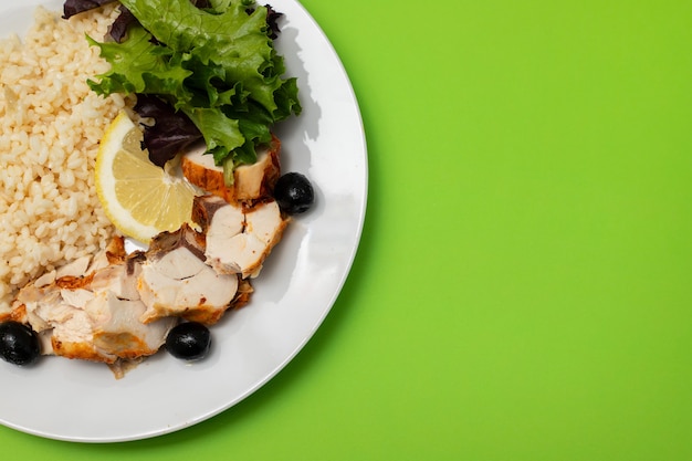 Chicken with boiled rice and salad on white plate