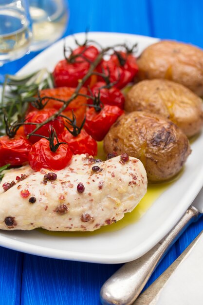 Chicken with potato and tomato on dish