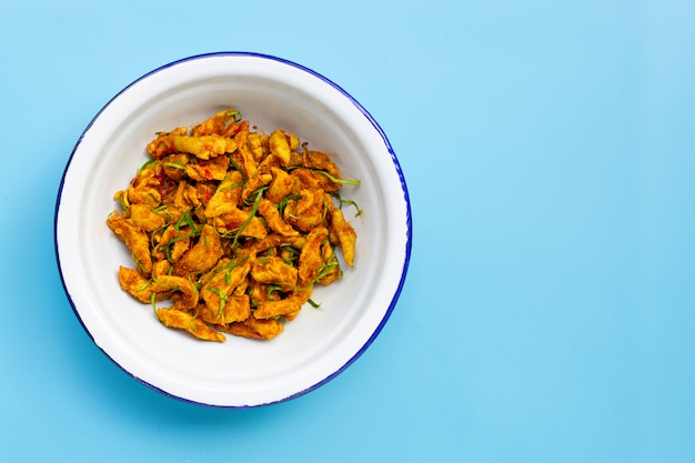 Chicken with yellow curry paste on blue background.  Spicy Thai food