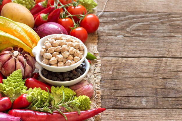 Chickpea in bowls with vegetables on a wooden table with copy space close up