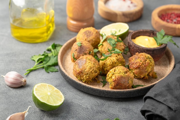 Falafel di ceci con lime e salsa su un piatto e un tavolo grigio