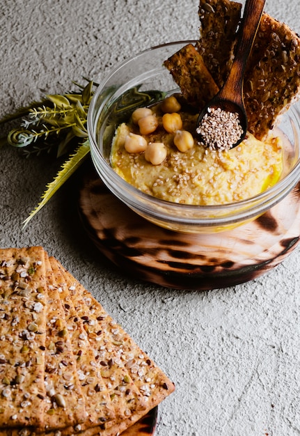 Chickpea hummus with sesame on white wooden board, top view. Vegan food