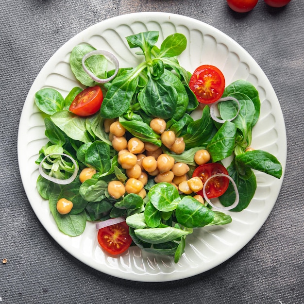 Insalata di ceci legumi, lattuga, mache, pomodoro fresco pasto sano spuntino dieta sul tavolo