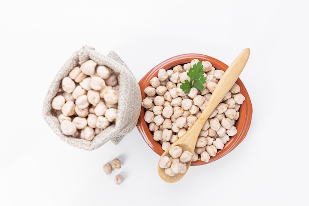 Chickpeas on a plate, bag and wooden spoon, top view, selective focus.