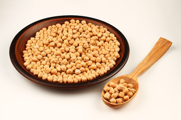 Chickpeas in a plate and spoon on a white surface