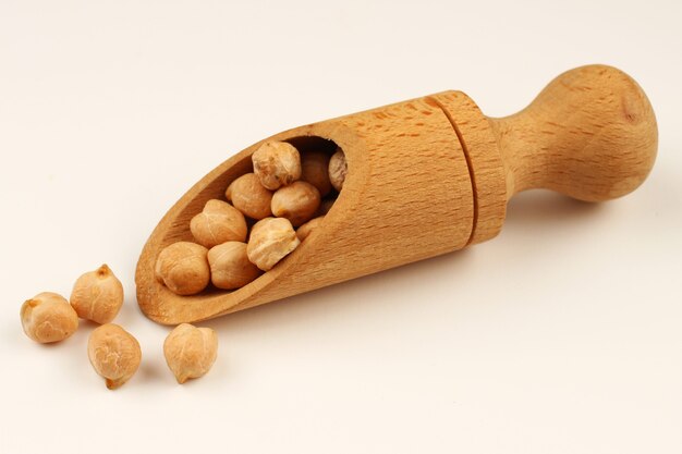 Chickpeas in a scoop on a white surface