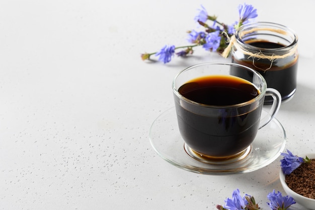 Chicory root coffee in glass cup and fresh flowers. Health Benefits. Copy space. Close up.