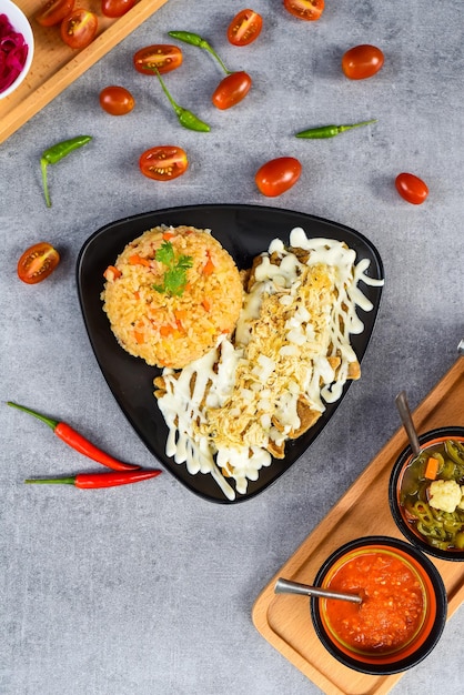 Чилакилес с рисом, мексиканскими соусами, перцем чили и помидорами черри, вид сбоку