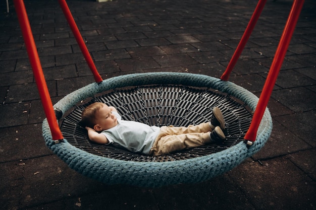 child 2-3 years old swings on a round swing in the playground