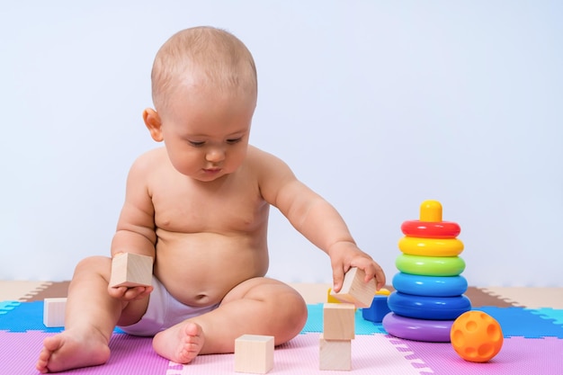 A child of 8-12 months assembles a tower of wooden cubes