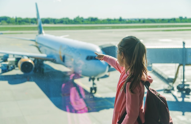 A child at the airport looks at the plane. Selective focus. Kid.