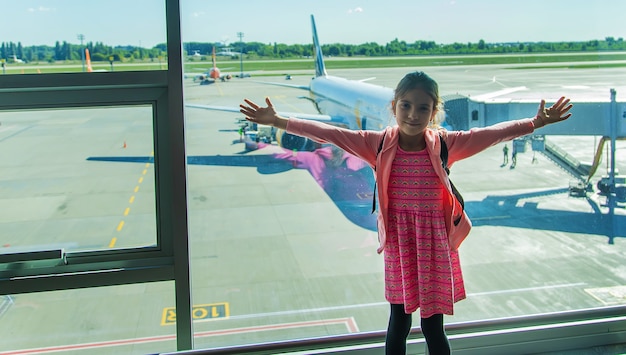 A child at the airport looks at the plane. Selective focus. Kid.