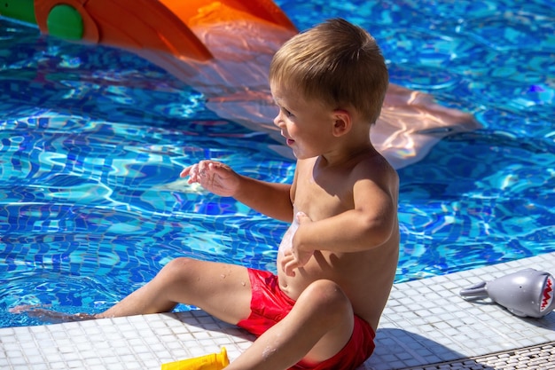 A child applying sunscreen to his stomach