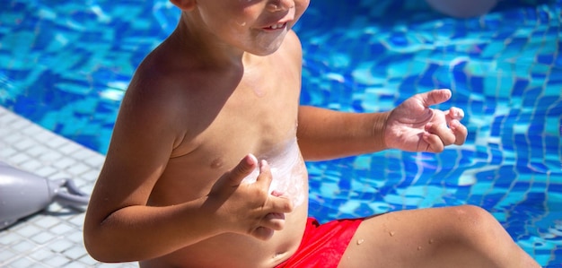 A child applying sunscreen to his stomach