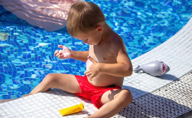 A Child Applying Sunscreen To His Stomach
