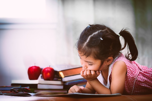 Child asian little girl is bored of reading a book. Vintage color tone