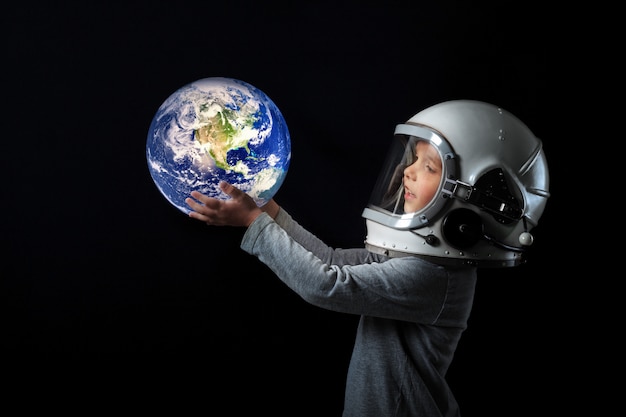 Foto il bambino nel casco di un astronauta tiene la terra tra le mani