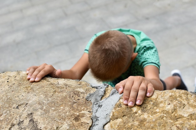 Child athlete falls off a cliff danger of falling from a hill\
climb a high mountain