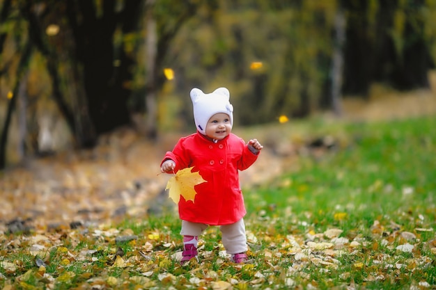 Child in autumn foliage takes its first steps