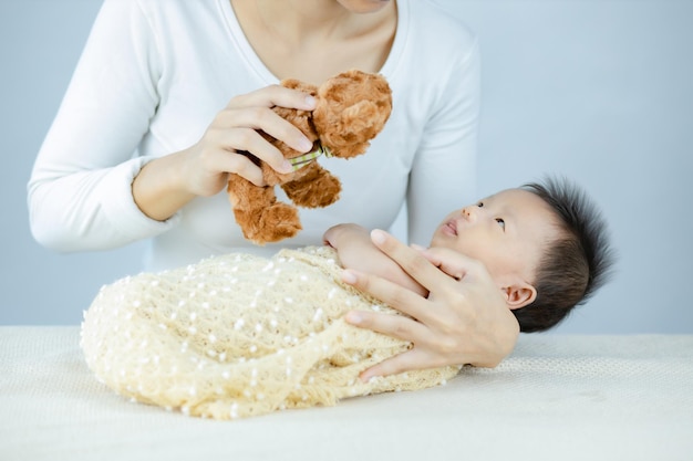 Child Baby looking at Hand holding teddy toy above baby.