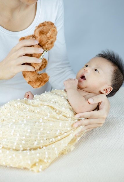 Child Baby looking at Hand holding teddy toy above baby.