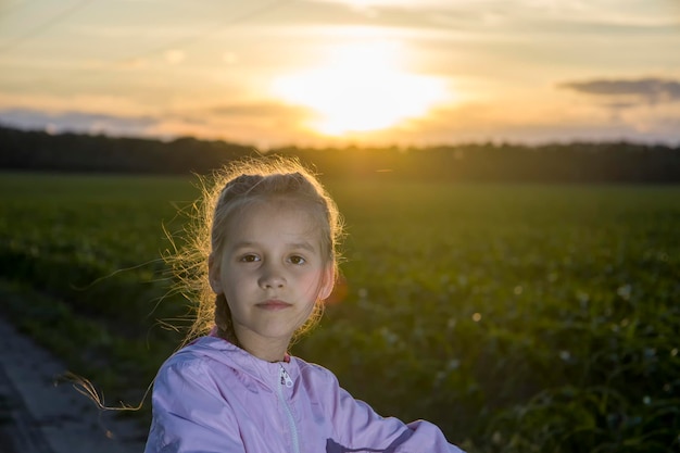 Child on a background of green field and with the rays of the evening sun