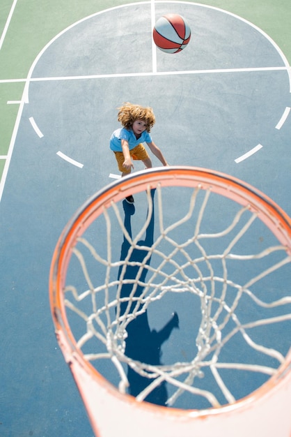 Child in basketball uniform jumping with basket ball for shot on basketball court