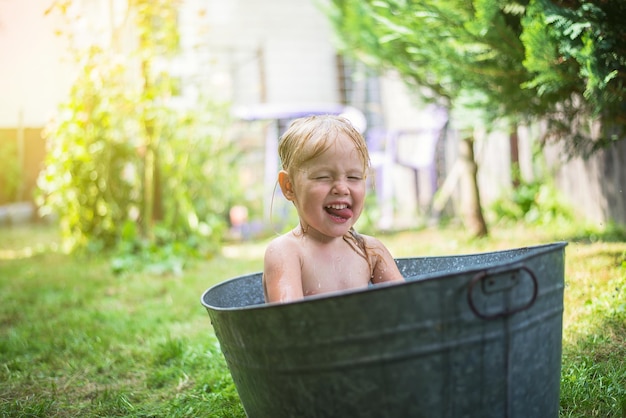 child bathes in the village in a galvanized bath