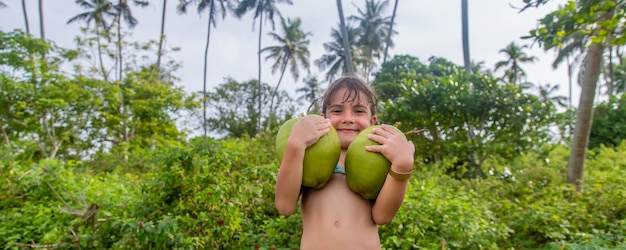 A child on the beach drinks coconut