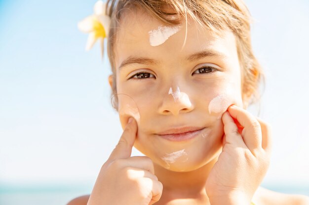 Child on the beach smears sunscreen. Selective focus.