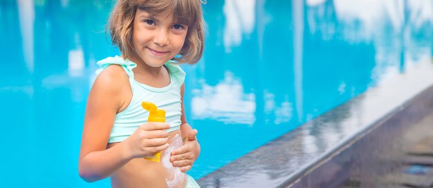 彼の背中に日焼け止めとビーチでの子供