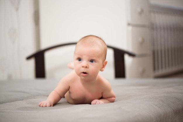 ベッドの上の子供。日当たりの良い寝室で遊ぶ男の子の赤ちゃん