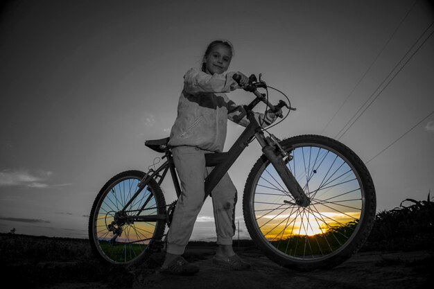 緑の野原を背景に、夕日の光で自転車に乗った子供