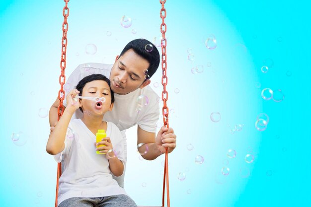 Child blowing soap bubbles with father on studio