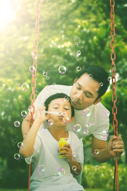 Child blowing soap bubbles with his father