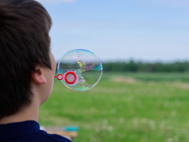 The child blows soap bubbles in nature