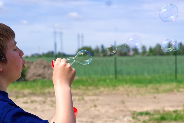 The child blows soap bubbles in nature