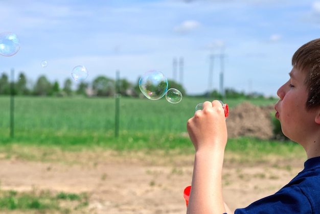 Il bambino soffia bolle di sapone in natura