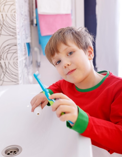 Child boy brushing his teeth in the bathroom Smiling child holding toothbrush
