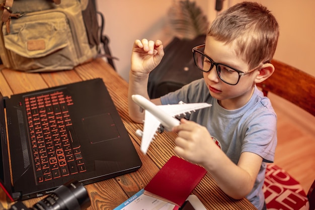 A child boy buys airline tickets for a laptop online at home Traveling is easy even a child can handle it