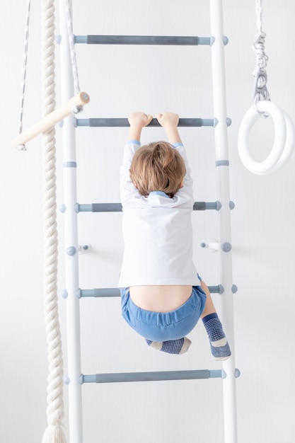 A child a boy climbs on the Swedish wall of the house