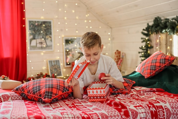 Child boy decorating Christmas tree at home. Family with kids celebrate winter holidays. Kids decorate living room and fireplace for Christmas. Bedroom new year decor