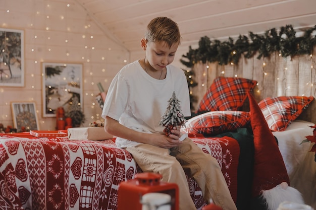 Child boy decorating Christmas tree at home. Family with kids celebrate winter holidays. Kids decorate living room and fireplace for Christmas.