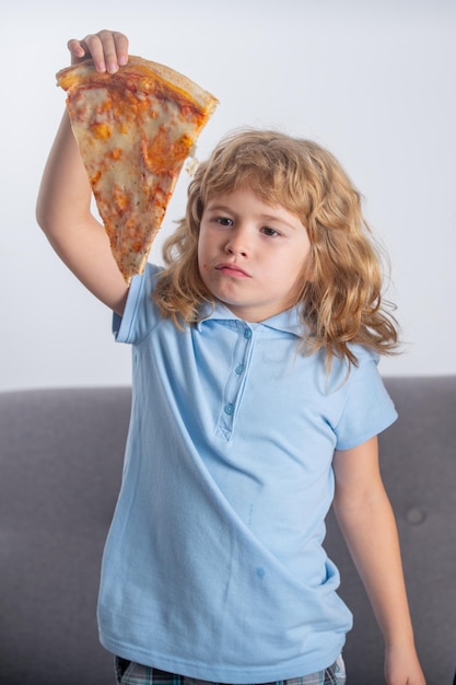 Фото Ребенок мальчик ест пиццу смешной ребенок держит кусок пиццы возле лица